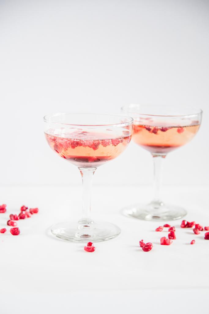 two finished cocktails with pomegranate seeds sprinkled around them