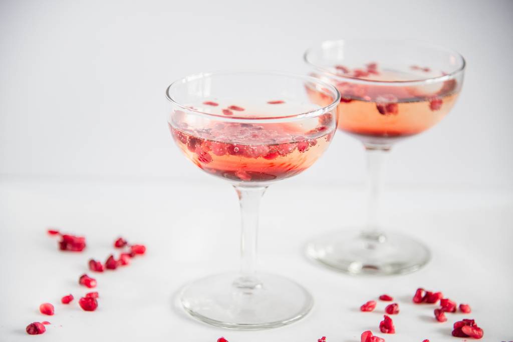 two glasses of pomegranate champagne with pomegranate seeds floating in them