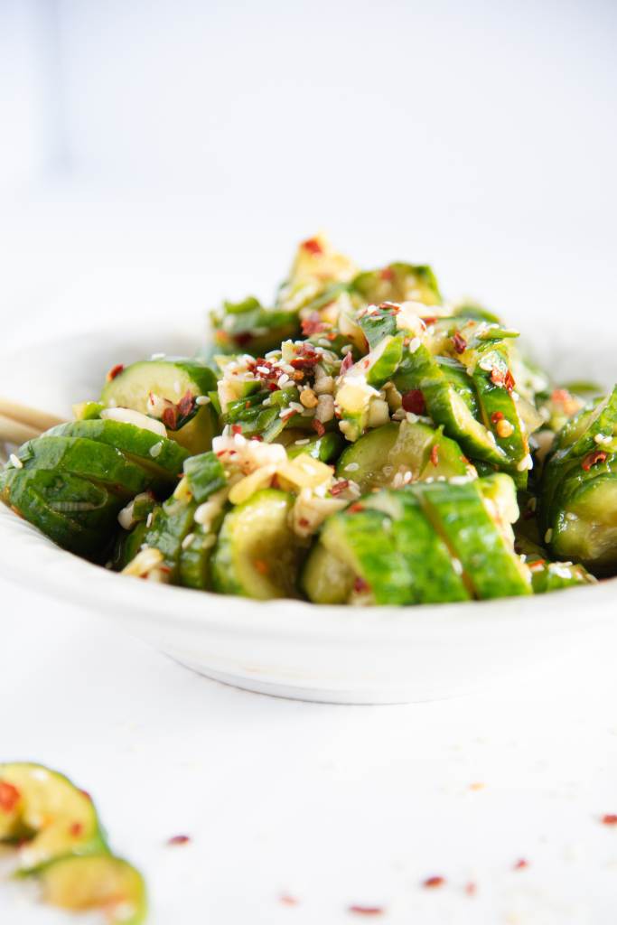 a bowl of spicy cucumber salad with some cucumber pieces sitting next to it 