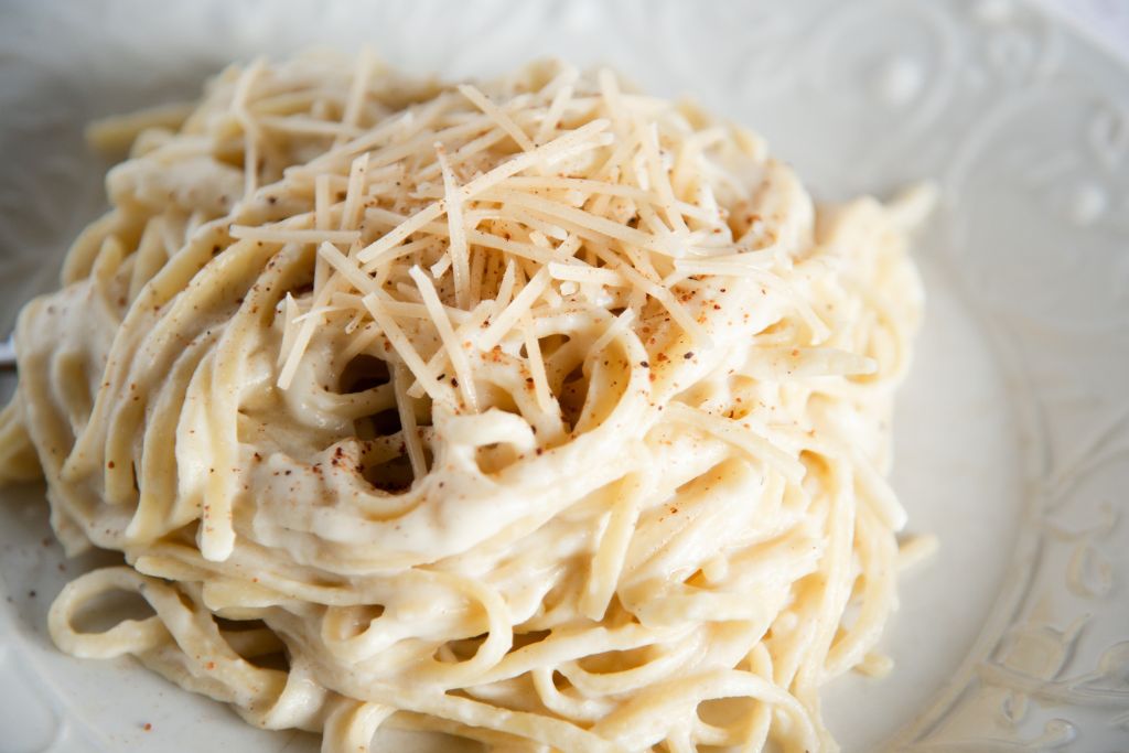 a close up of cauliflower Alfredo sauce covered noodles, with cheese and nutmeg sprinkled on top