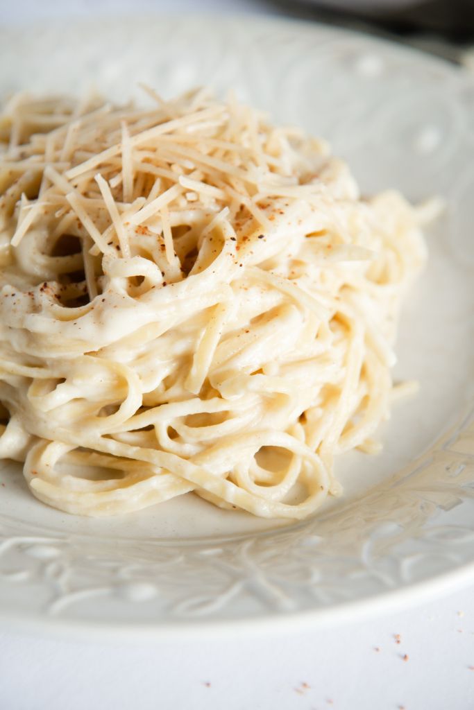 a close up of noodles cover in a sauce on a white plate