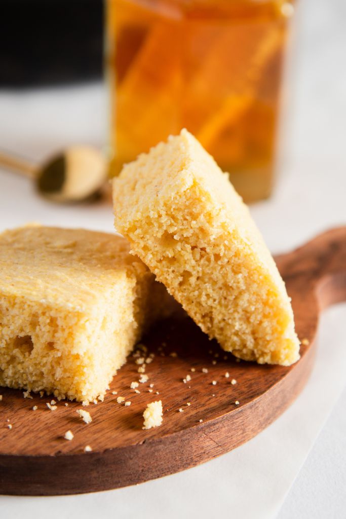 a piece of cornbread lined against another piece of cornbread, you can also see a jar of honey behind them