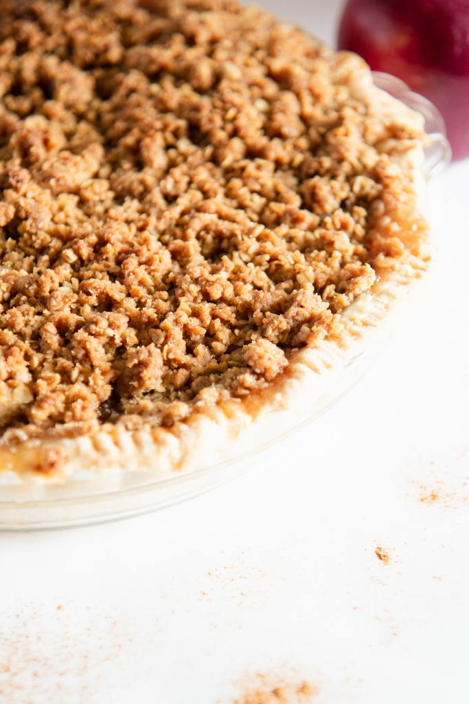 a close up of a dutch apple pie, you can see part of a whole apple behind it