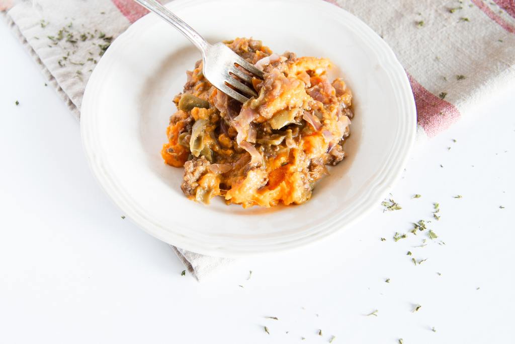 a fork full of shepherd's pie being held over a plate of shepherd's pie