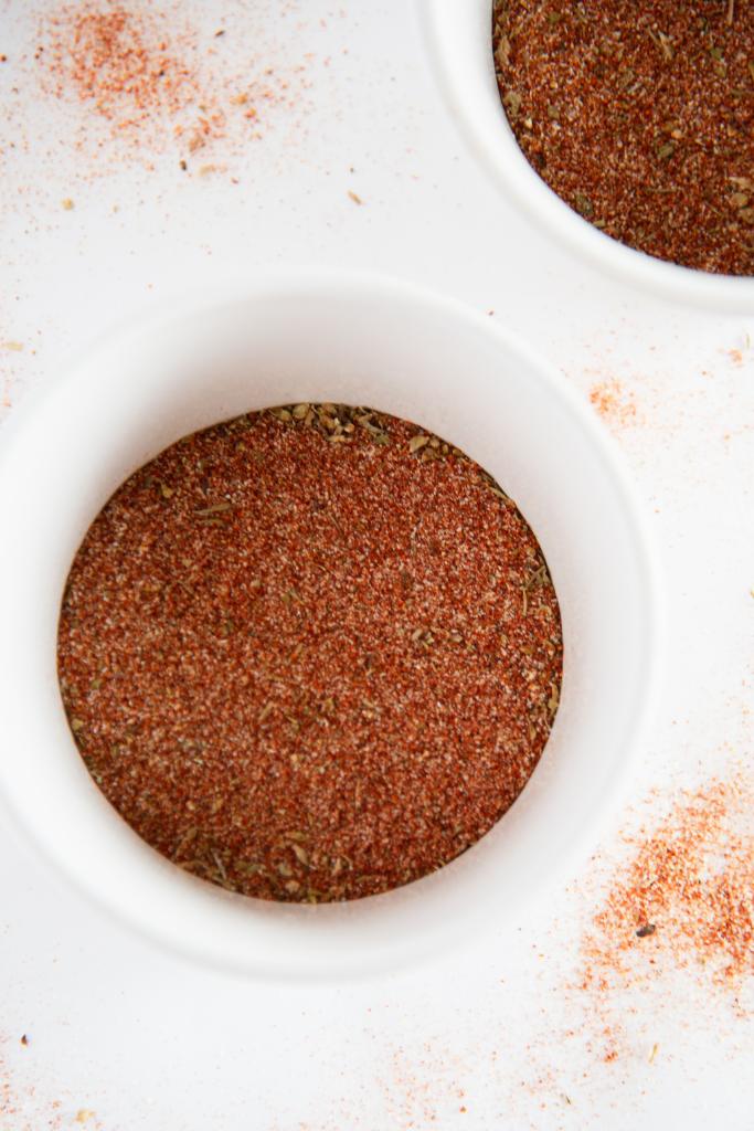 a small white bowl of blackening seasoning, you can see part of another bowl of seasoning next to it