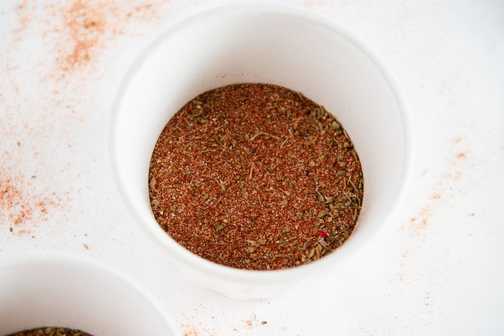 a small white bowl with blackening seasoning, you can part of another bowl to the left of it