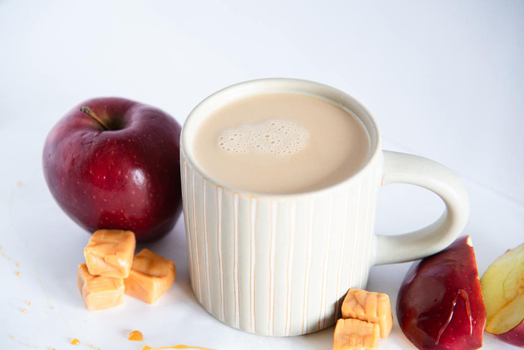 a finished latte with apples and caramel pieces around it