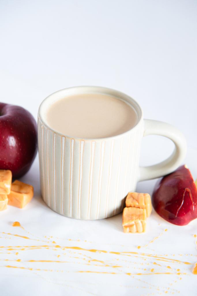 a finished latte with caramel pieces and apples around it