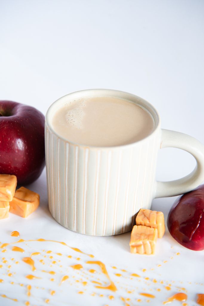 a finished latte with caramel pieces around it, and caramel drizzled in front of it