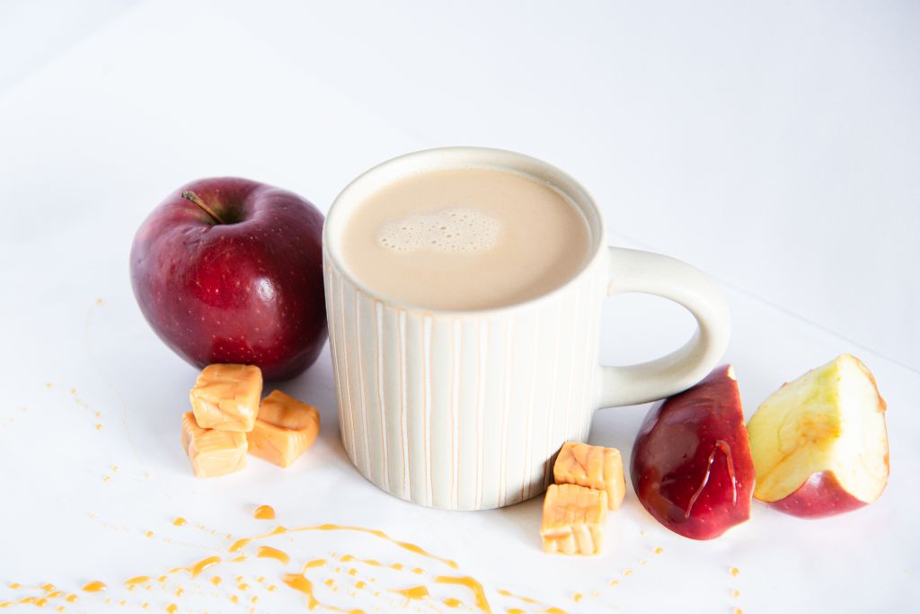 a caramel apple latte, with apples and caramel pieces around it