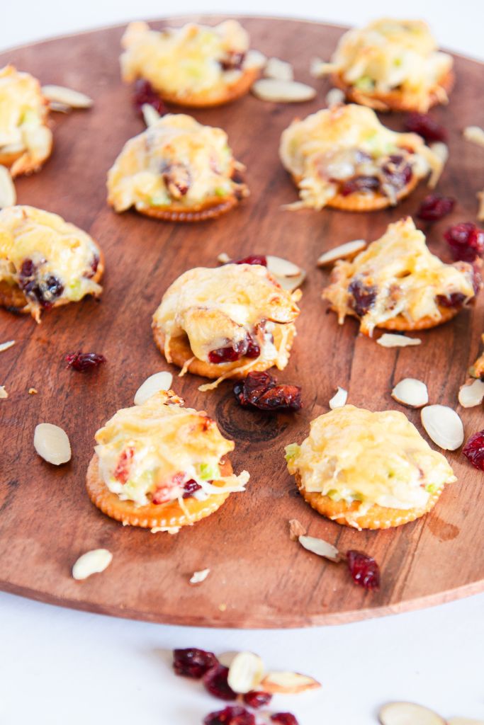 chicken salad bites on a tray with dried cranberries and almonds around them