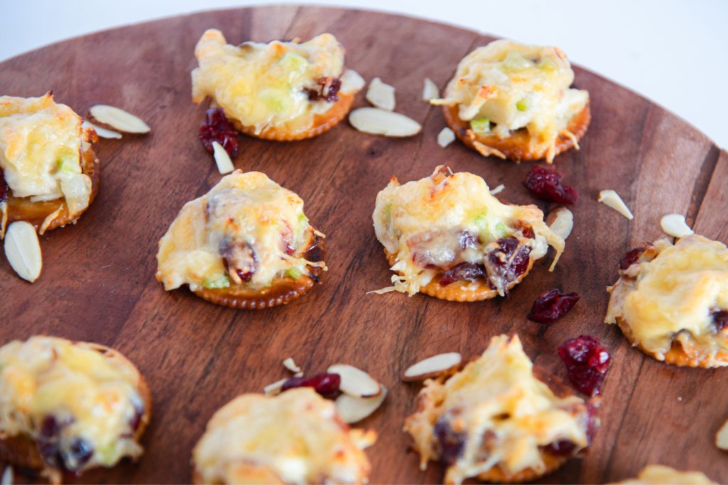 chicken salad bites on a wooden tray with almonds and dried cranberries around them