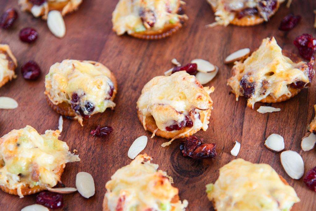 chicken salad bites on a wooden tray with cranberries and almonds around them