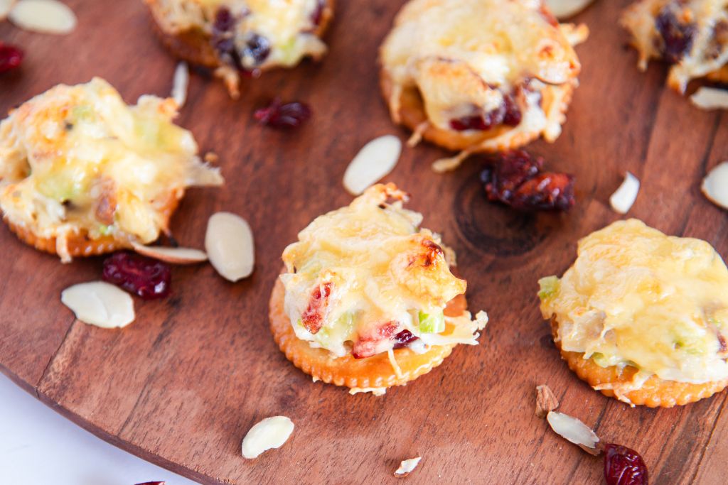 a close up of chicken salad bites with almonds and dried cranberries around them