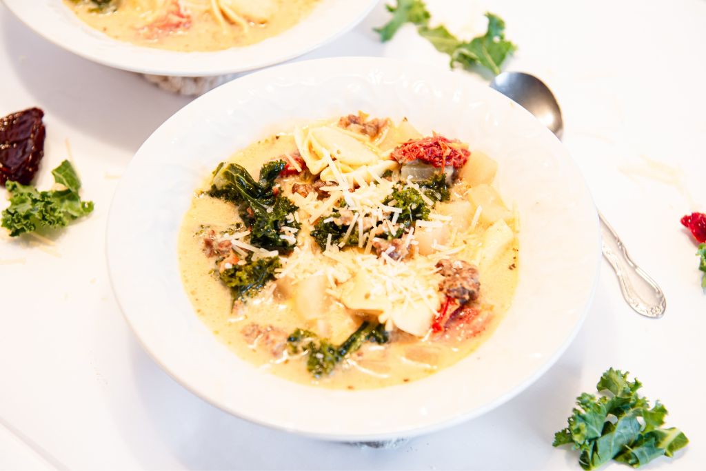 two bowls of soup with cheese sprinkled on top, one of the bowls has a spoon next to it