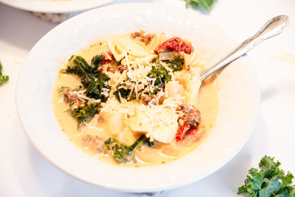 a bowl of soup with a spoon in it and shredded cheese sprinkled on top