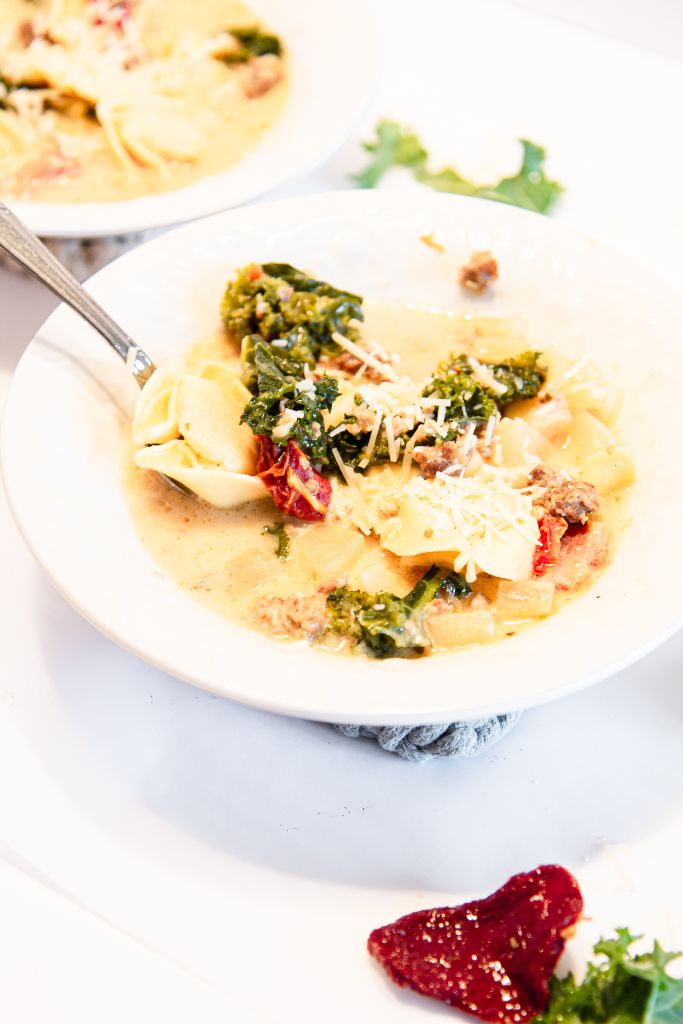 a bowl of soup with a spoon in it, you can see part of another bowl behind it