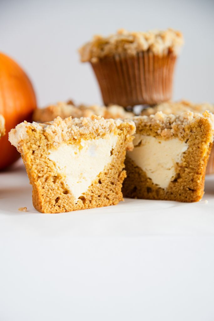 a close up of a muffin that has been cut in half to show the cheesecake filling