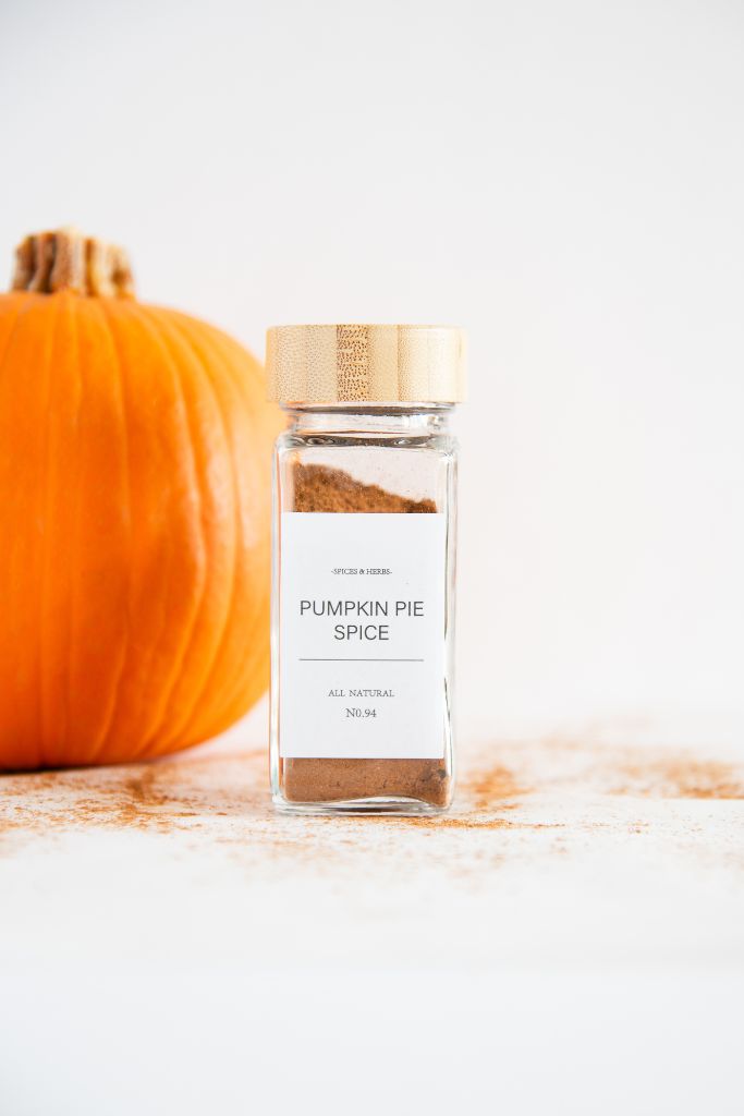 a bottle pumpkin pie spice with a label on it, you can see part of a pumpkin behind it