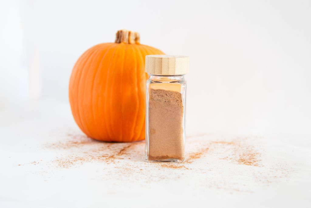 a bottle of pumpkin pie spice with a pumpkin behind it