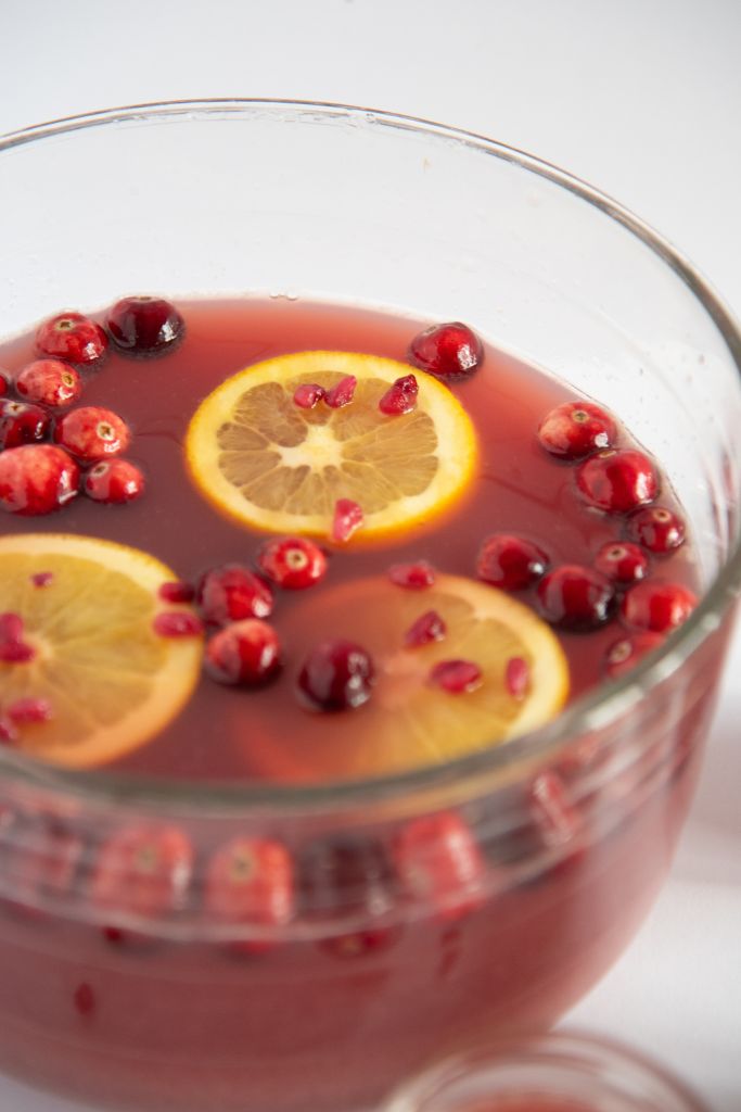 a bowl of punch with cranberries and orange slices floating in it 