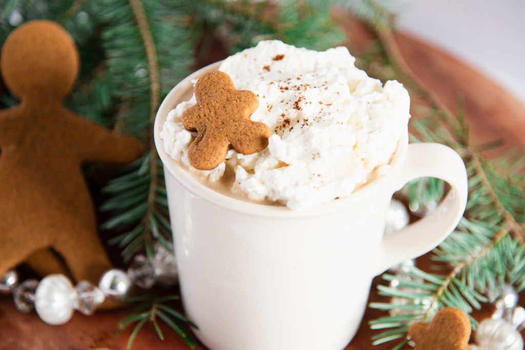 a gingerbread latte, with pine branches and gingerbread cookies around it