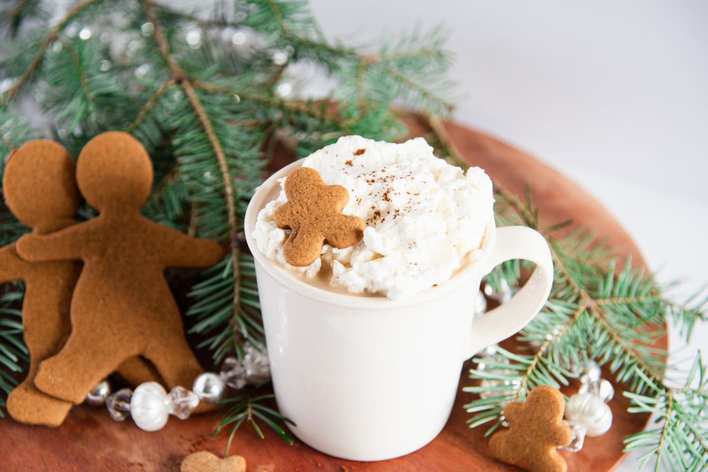 a finished gingerbread latte with pine branches and cookies around it 