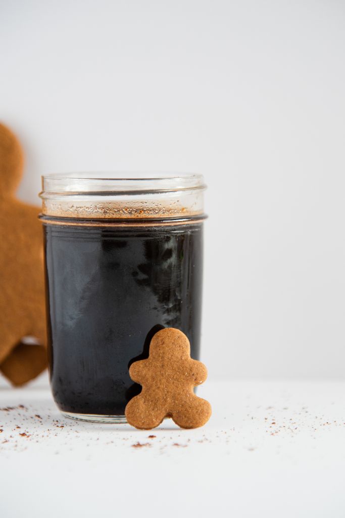 a close up of a jar of gingerbread syrup with a gingerbread man lined against it