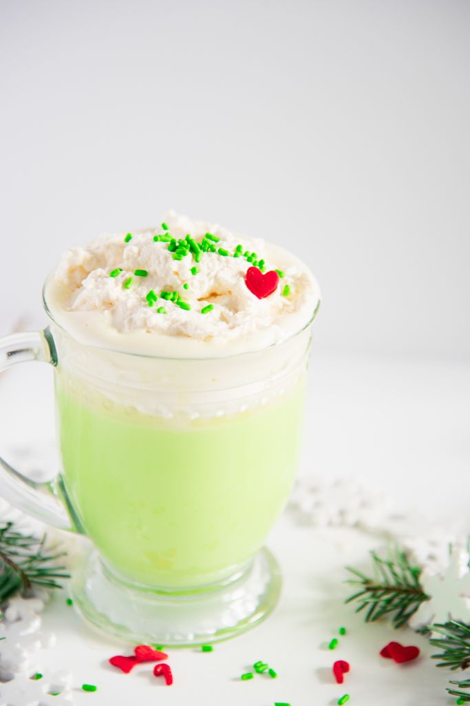 a close up of the whipped cream and sprinkles  on top of grinch hot chocolate 