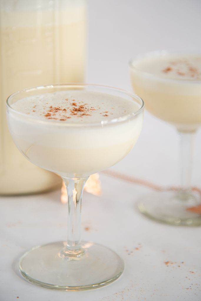 a glass of eggnog, there is another glass and a gold star behind it