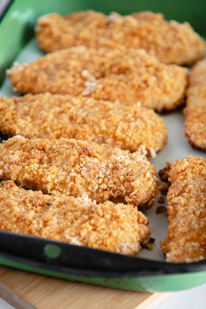 a green dish of fried chicken on a wooden board 