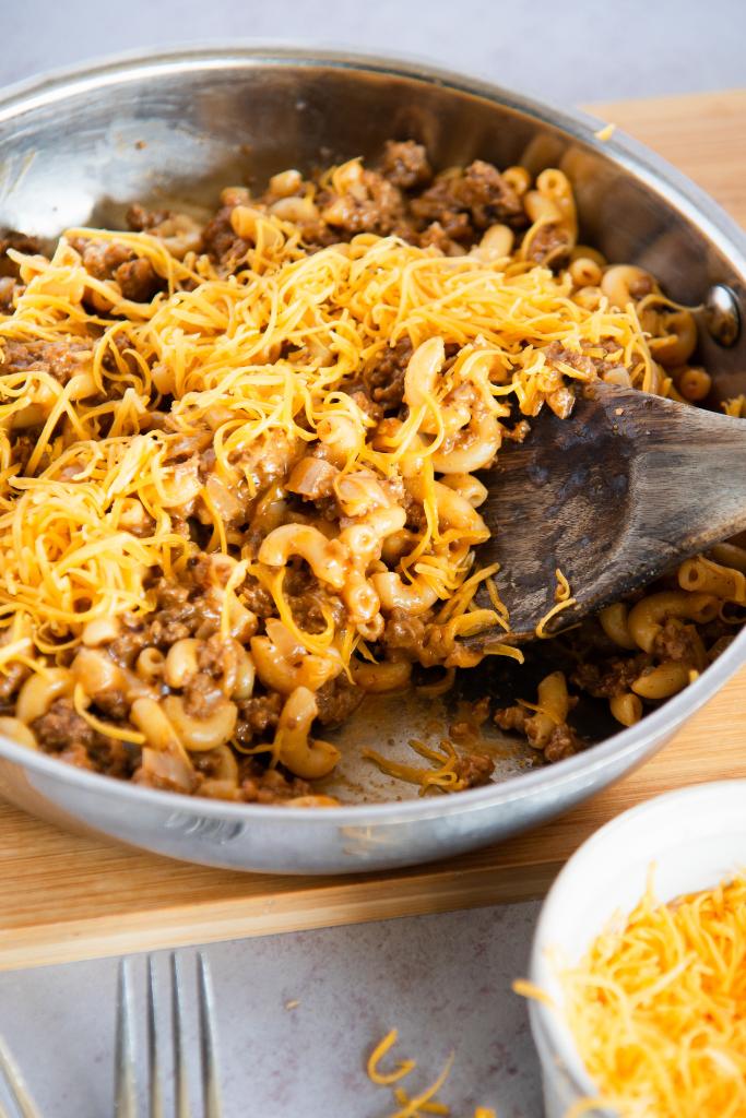 someone taking a scoop of hamburger out of a pan