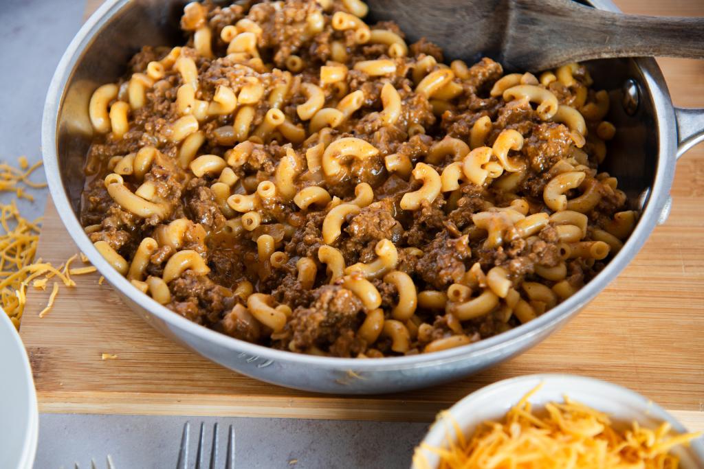 a pan of hamburger helper with a wooden spoon in it 