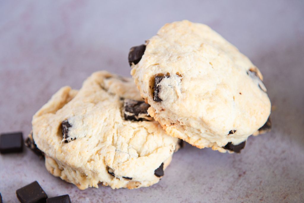 a close up of two biscuits with some chocolate chunks next to them