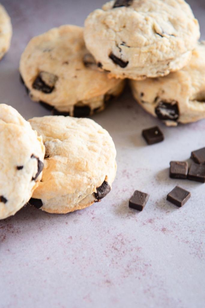 an overhead shot of chocolate chunk biscuits on a table with chocolate chunks next to them