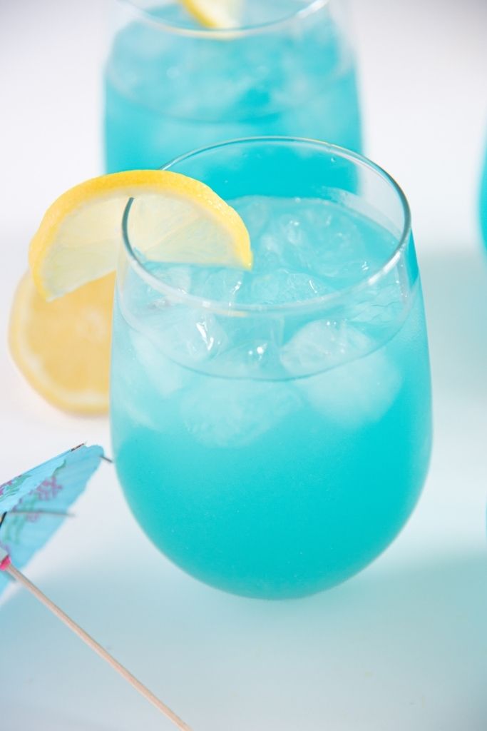 a glass of of lemonade with a drink umbrella next to it 