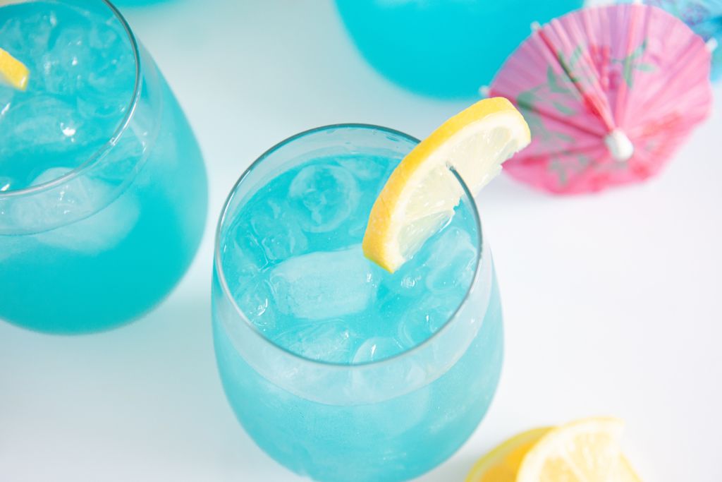 an overhead shot of a glass of lemonade with lemon slices next to it