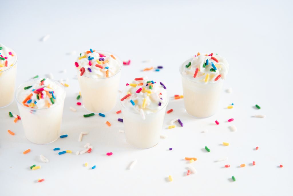 an overhead shot of finished birthday cake shots with sprinkles around them