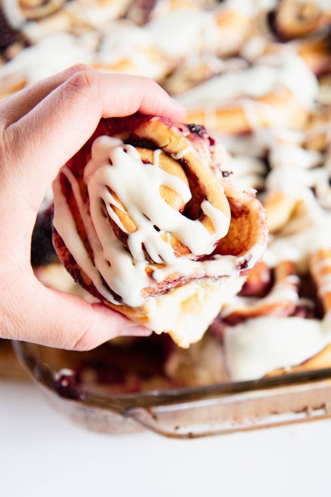 someone holding a sweet roll, turned so you can see the top of it 