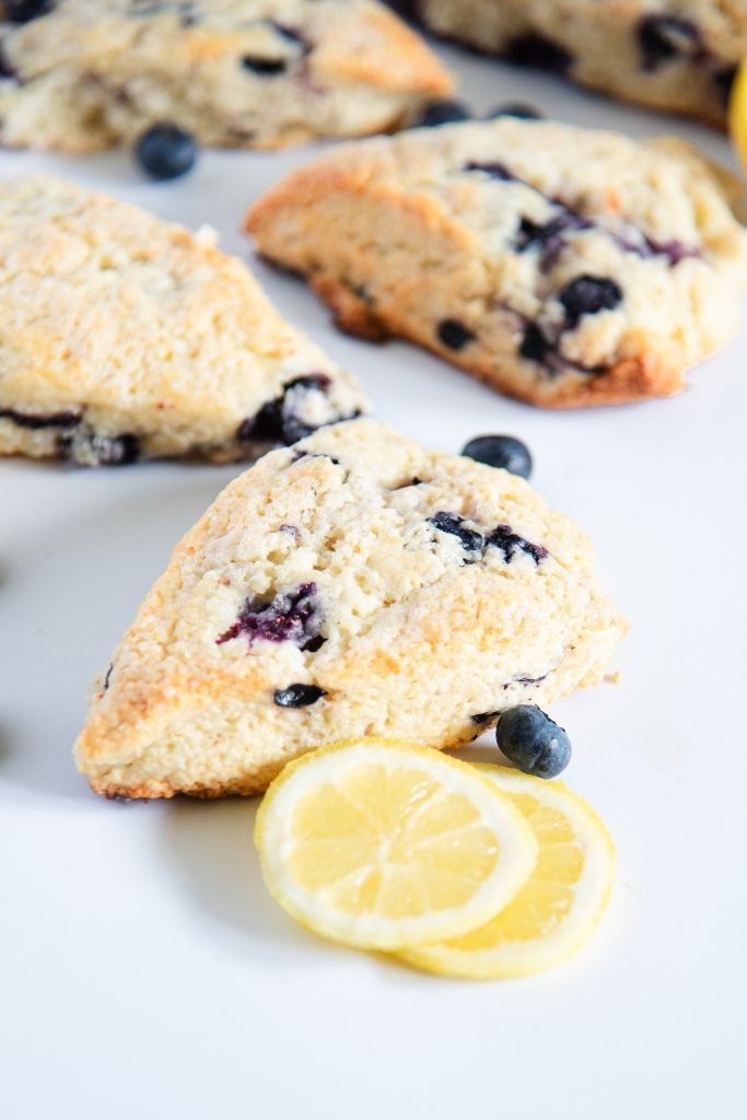 a scone with lemon slices next to it, you can seen more scones behind it 