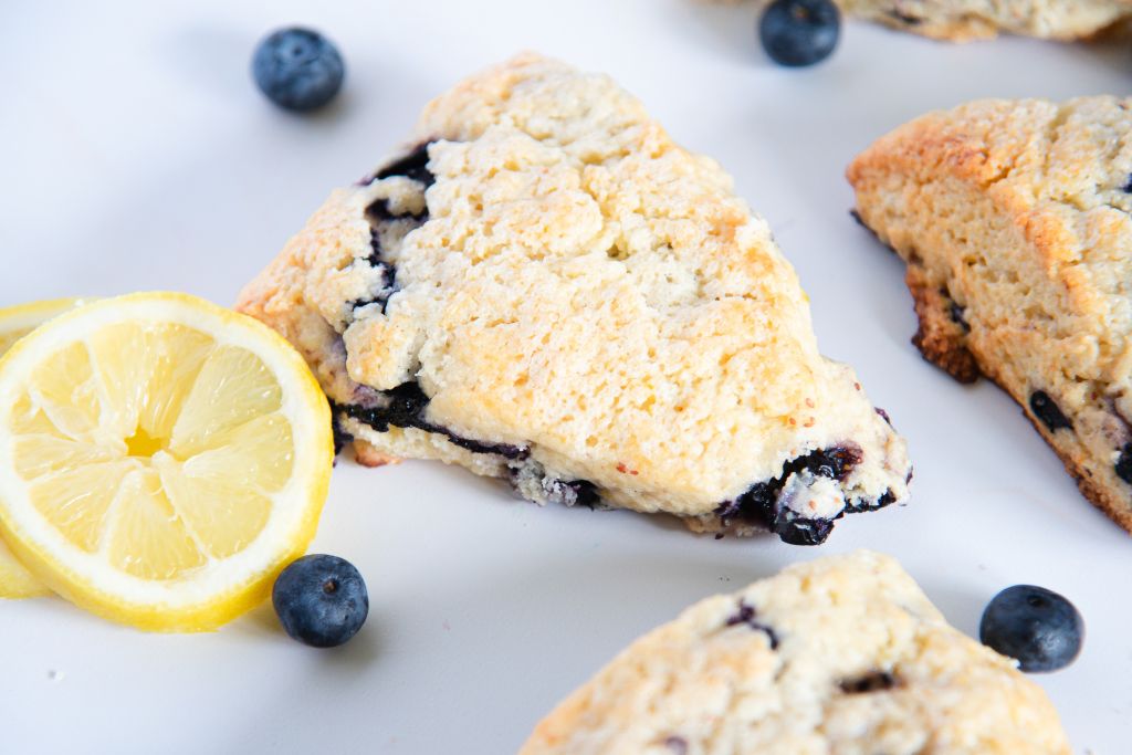 a close up of a scone with lemon slices and blueberries by it 