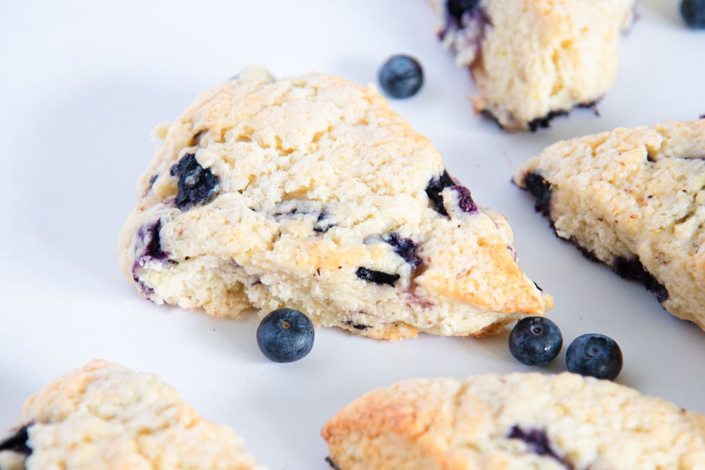 a close of a scone with blueberries around it 