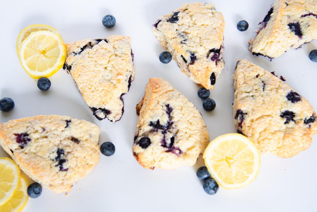 an overhead shot of six scones with lemon slices and blueberries around them