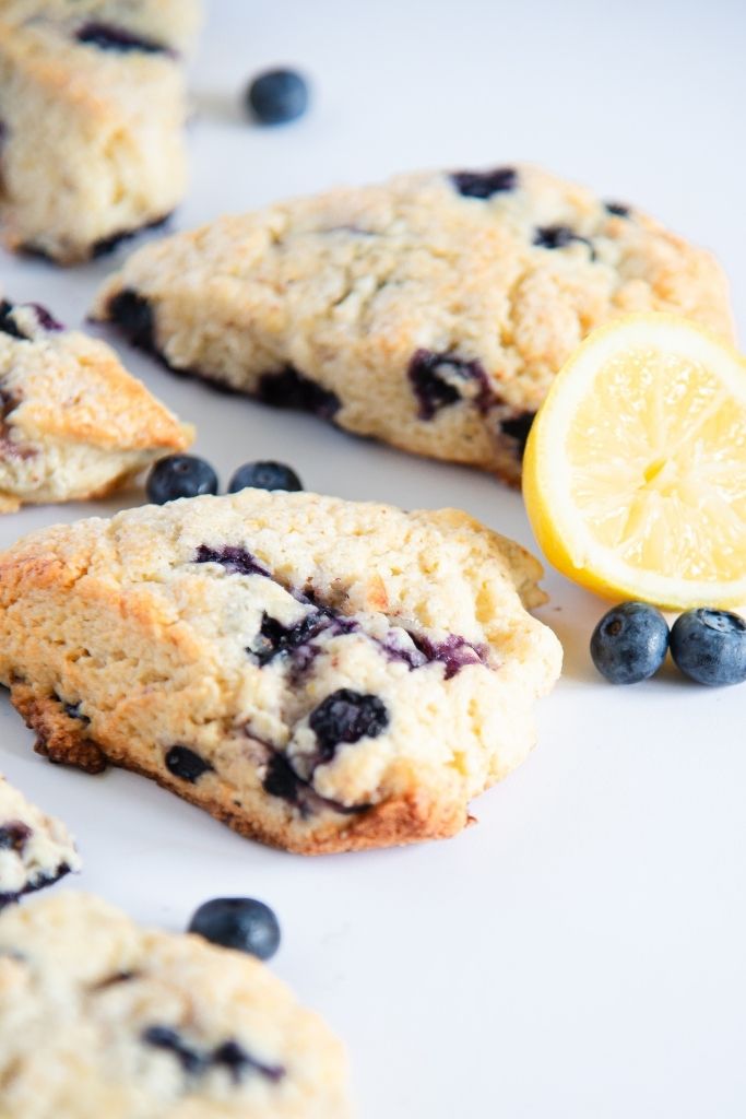 a close up of scones with a lemon slice and some blueberries by them