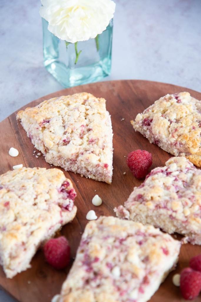scones on a wooden plate with a white rose next to them 