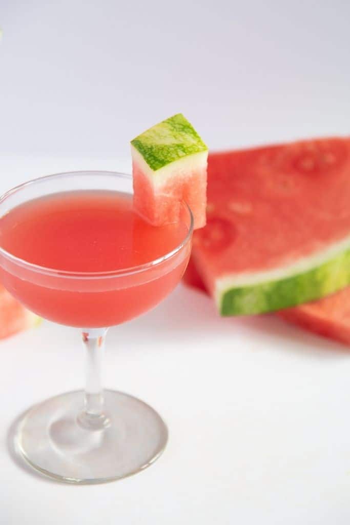 a finished cocktail in front of two watermelon slices 