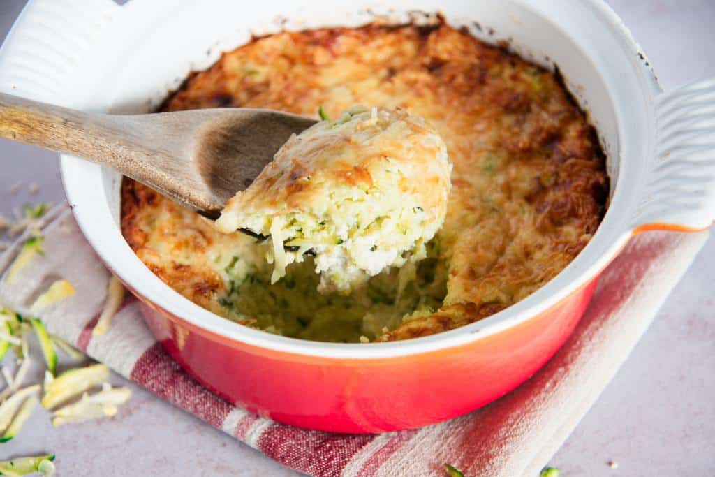 a spoonful of casserole being held over a dish of casserole