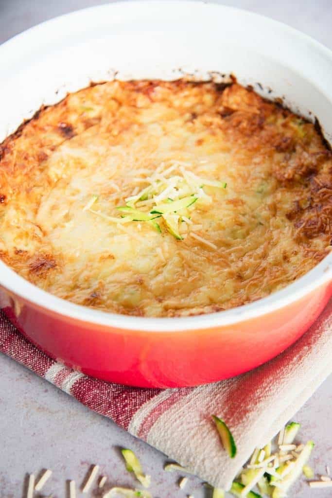 a dish of zucchini casserole with cheese on top