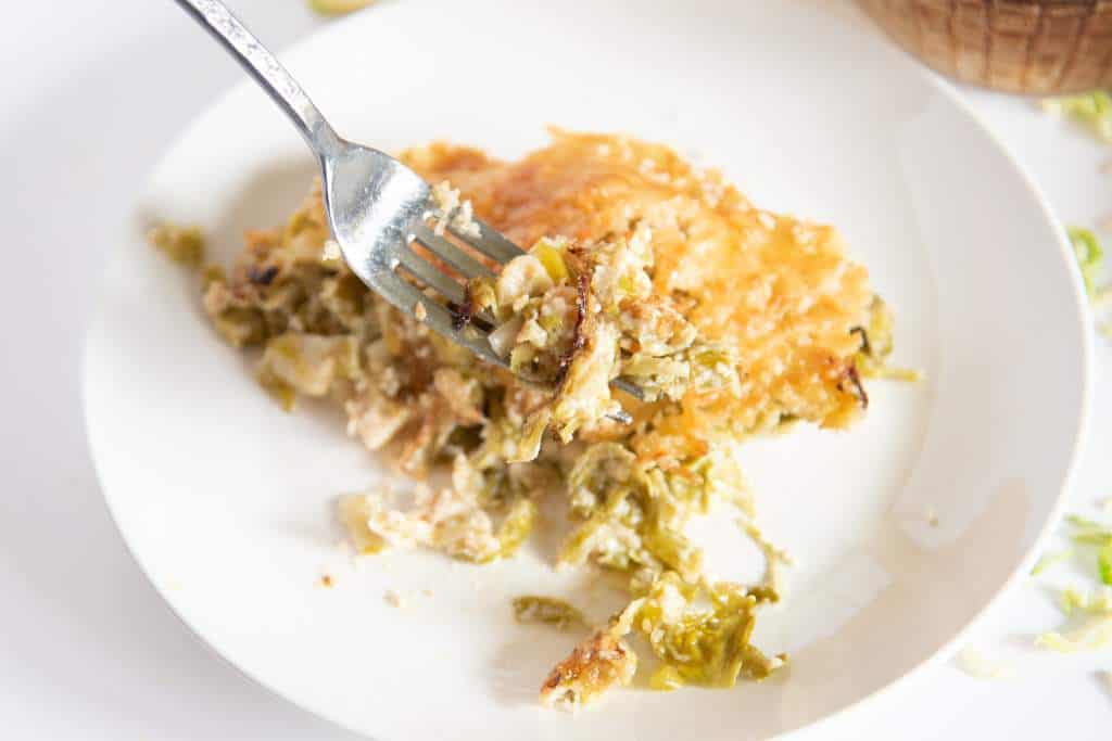 a fork full of gratin being held over a plate of gratin 