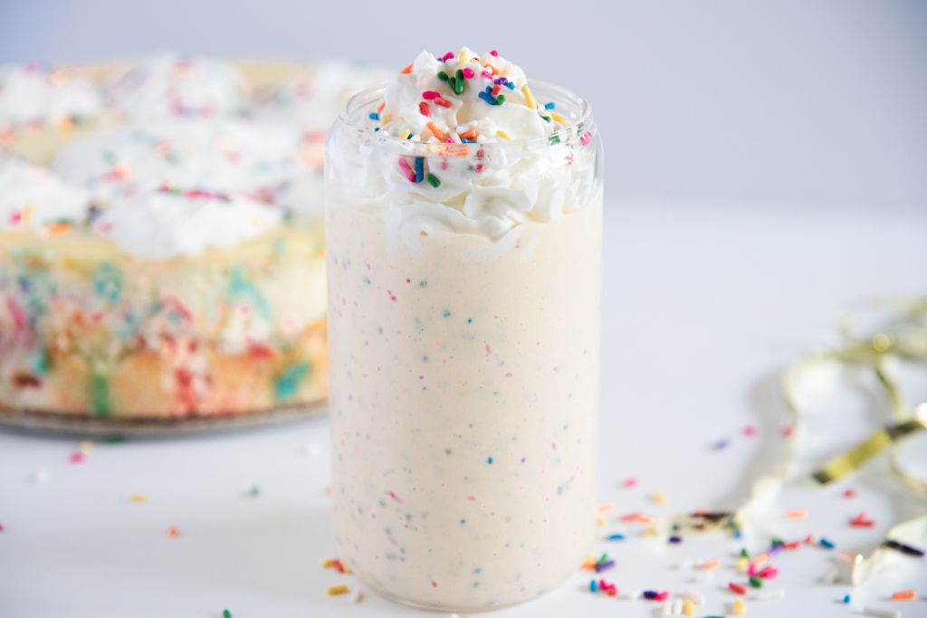 a finished milkshake with a cake behind it